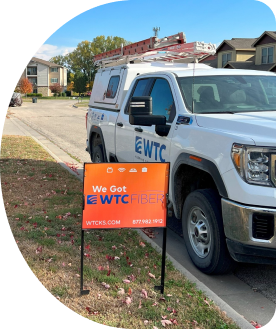 WTC service truck parked beside a WTC Fiber sign in the ground